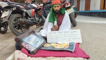 শরীরে কাফনের কাপড় জড়িয়ে বিষের বোতল নিয়ে সাংবাদিকের অবস্থান